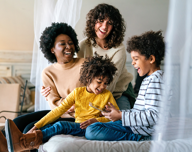 Family children gay parents concept. Happy multiethnic women couple having fun with kids at home